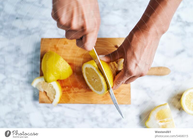 Hände einer Frau beim Zitronenschneiden auf einem Schneidebrett Innenaufnahme Innenaufnahmen innen drinnen Nahaufnahme close up close-up close ups close-ups