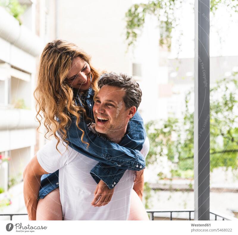 Verspieltes glückliches Paar in Nachtwäsche auf dem Balkon Balkone verspielt spielerisch Glück glücklich sein glücklichsein Pärchen Paare Partnerschaft Zuhause