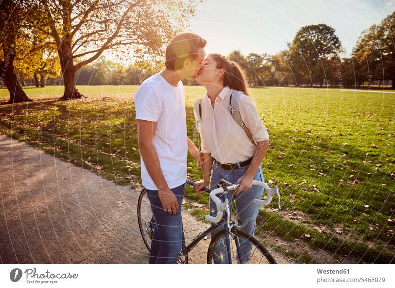 Junges verliebtes Paar küsst sich in einem Park Parkanlagen Parks Pärchen Paare Partnerschaft küssen Küsse Kuss Mensch Menschen Leute People Personen