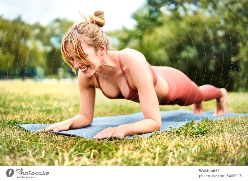 Athletin bei Plankenübungen im Freien im Park ausüben trainieren Übung freuen Frohsinn Fröhlichkeit Heiterkeit Glück glücklich sein glücklichsein Muße