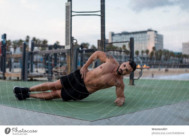 Barechested muskulösen Mann tun Seite Planken im Freien Unterarmstütz Planks trainieren Muskeln athletisch Workout Männer männlich Mensch Menschen Leute People