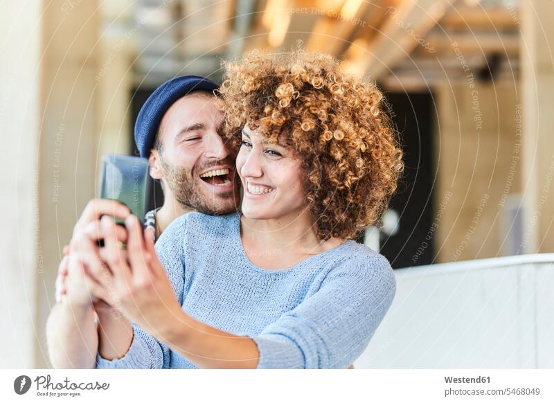 Lachendes Paar bei einem Selfie Deutschland leger Beanie Beanies Selfies Smartphone iPhone Smartphones Selbstportrait sich selbst fotografieren