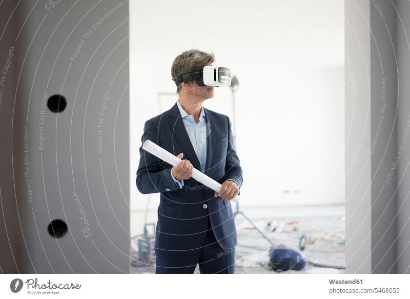 Mann im Anzug mit VR-Brille in einem im Bau befindlichen Gebäude Männer männlich Baustelle Baustellen Anzuege Anzüge Brillen virtuell Virtualität Erwachsener