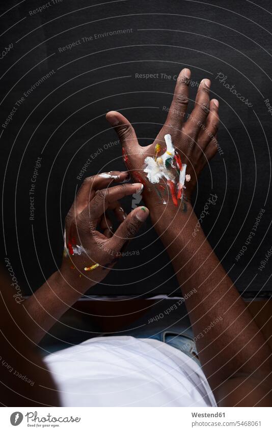 Schmutzige Hände des Künstlers mit bunten Farben vor schwarzem Hintergrund. London, UK. Leute Menschen People Person Personen Afrikanisch