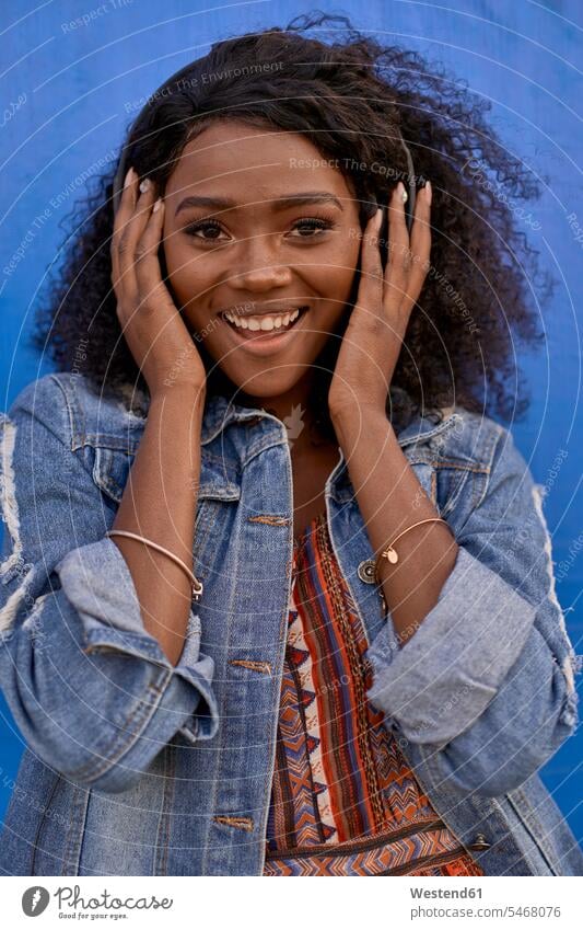 Porträt einer glücklichen jungen Frau, die mit Kopfhörern Musik hört Leute Menschen People Person Personen Afrikanisch Afrikanische Abstammung dunkelhäutig