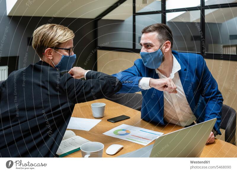 Maskierte Unternehmer und Unternehmerinnen bei der Begrüßung mit Ellbogenstoß im Sitzungssaal während einer Coronavirus-Pandemie Farbaufnahme Farbe Farbfoto