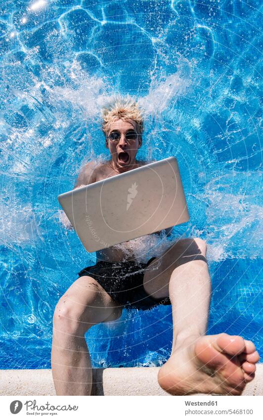 Schockierter junger Mann mit Laptop in Schwimmbad gefallen Farbaufnahme Farbe Farbfoto Farbphoto Spanien Freizeitbeschäftigung Muße Zeit Zeit haben