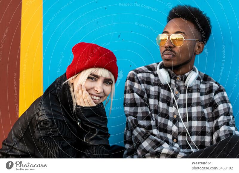Porträt eines jungen Paares vor blauer Wand Leute Menschen People Person Personen Europäisch Kaukasier kaukasisch Afrikanisch Afrikanische Abstammung
