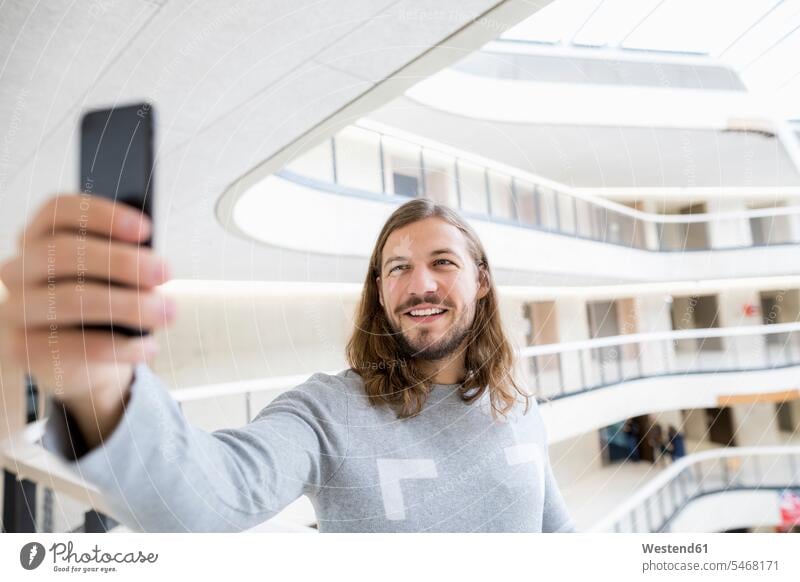 Porträt eines lächelnden Mannes, der ein Selfie mit seinem Handy macht Männer männlich Smartphone iPhone Smartphones Selfies Portrait Porträts Portraits