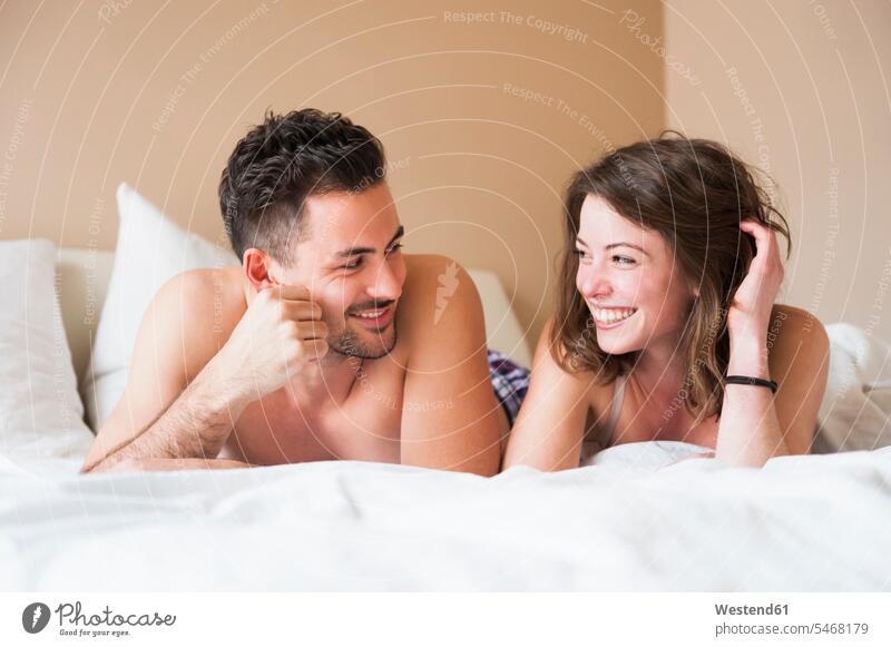 Glückliches junges Paar, das sich zu Hause im Bett ansieht Farbaufnahme Farbe Farbfoto Farbphoto Innenaufnahme Innenaufnahmen innen drinnen Tag
