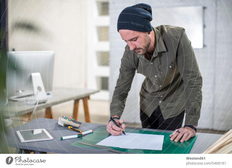 Junger Mann macht Notizen am Schreibtisch im Büro Office Büros Männer männlich notieren Arbeitstisch Schreibtische Arbeitsplatz Arbeitsstätte Arbeitstelle