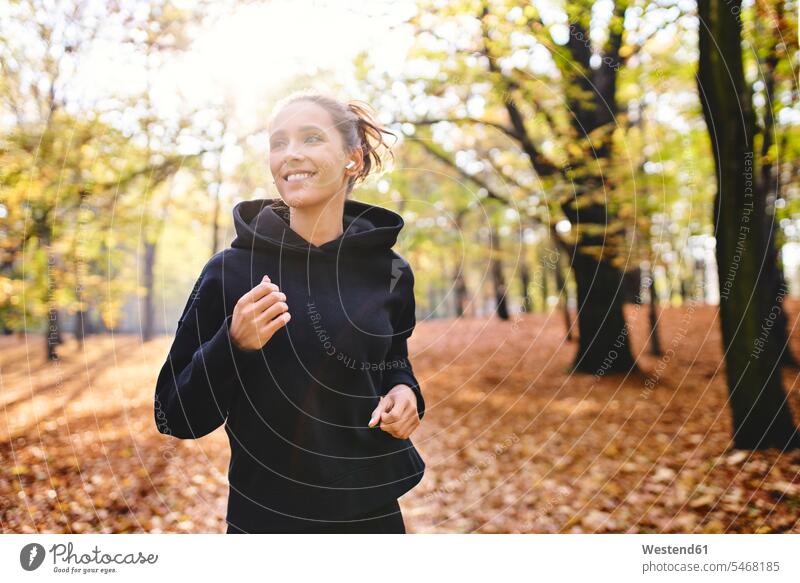 Junge Frau joggt im Herbstwald rennen freuen Glück glücklich sein glücklichsein zufrieden schwarze schwarzen schwarzer schwarzes Muße Anreiz Ansporn Antrieb
