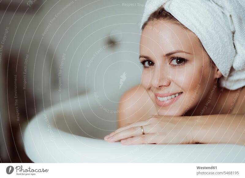 Porträt einer lächelnden Frau mit Handtuch um den Kopf, die ein Bad zu Hause nimmt weiblich Frauen baden Handtuecher Handtücher Portrait Porträts Portraits