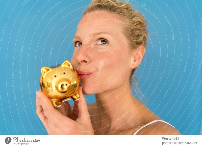 Porträt einer blonden Frau, die ein goldenes Sparschwein küsst Leute Menschen People Person Personen Europäisch Kaukasier kaukasisch 1 Ein ein Mensch