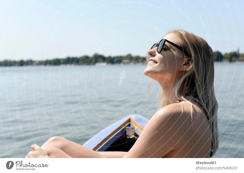Deutschland, Brandenburg, lächelnde blonde Frau beim Sonnenbad am Zeuthener See weiblich Frauen Seen blonde Haare blondes Haar sonnenbaden sich sonnen