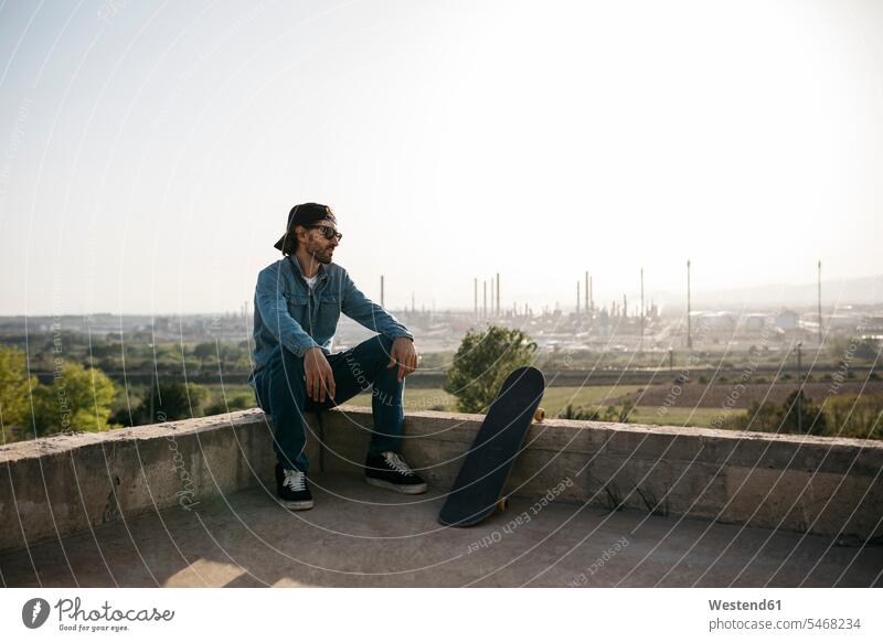 Skateboarder in Freizeitkleidung ruht bei Sonnenuntergang Erholung erholen Jeans Jeanshose zwanglos ungezwungen casual lässig leger Zwanglosigkeit sitzen