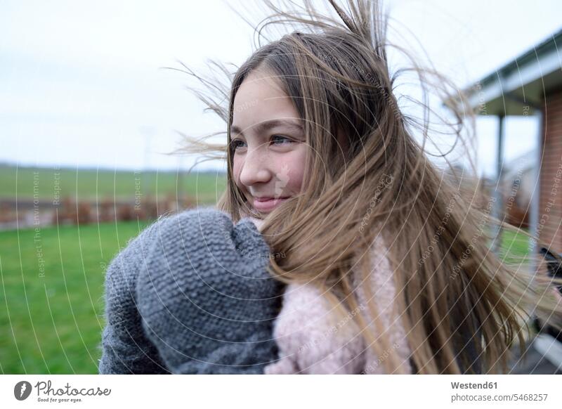 Porträt eines lächelnden Mädchens mit wehenden Haaren im Winter weiblich Portrait Porträts Portraits winterlich Winterzeit Kind Kinder Kids Mensch Menschen