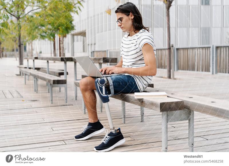 Kontemplation eines Mannes mit Prothese am Laptop auf einer Bank in der Stadt Farbaufnahme Farbe Farbfoto Farbphoto Spanien Außenaufnahme außen draußen