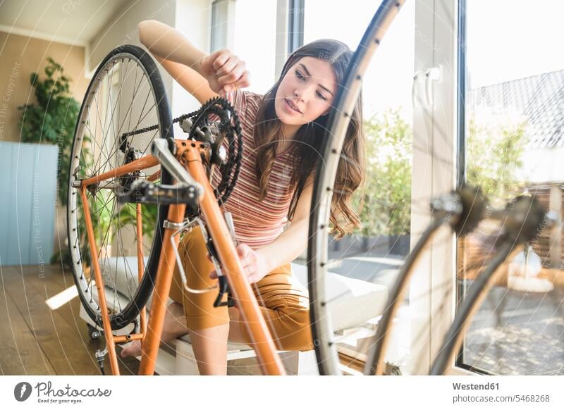 Junge Frau repariert Fahrrad zu Hause Bikes Fahrräder Räder Rad Zuhause daheim weiblich Frauen reparieren Reparatur Raeder Erwachsener erwachsen Mensch Menschen