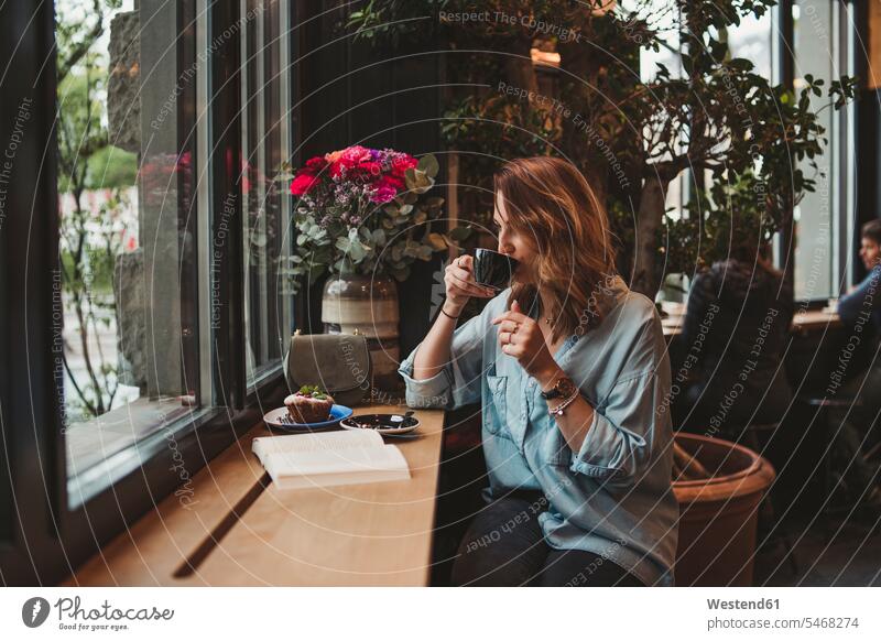Junge Frau trinkt aus Kaffeetasse in einem Café Leute Menschen People Person Personen Europäisch Kaukasier kaukasisch Nordeuropäisch 1 Ein ein Mensch