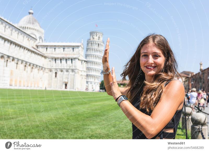 Italien, Pisa, Porträt einer jungen Frau, die mit dem schiefen Turm im Hintergrund posiert Pose posieren Portrait Porträts Portraits Türme Tuerme weiblich