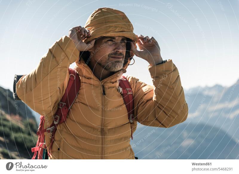 Österreich, Tirol, Porträt eines Mannes mit Kapuzenjacke bei einer Wanderung in den Bergen Portrait Porträts Portraits Männer männlich Gebirge Berglandschaft