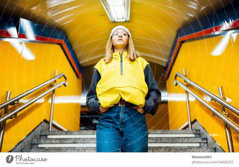 Junge Frau geht in der U-Bahn-Station die Treppe hinunter Touristen Brillen gehend allein Farben Farbtoene Farbton Farbtöne gelbe gelber gelbes stehend steht