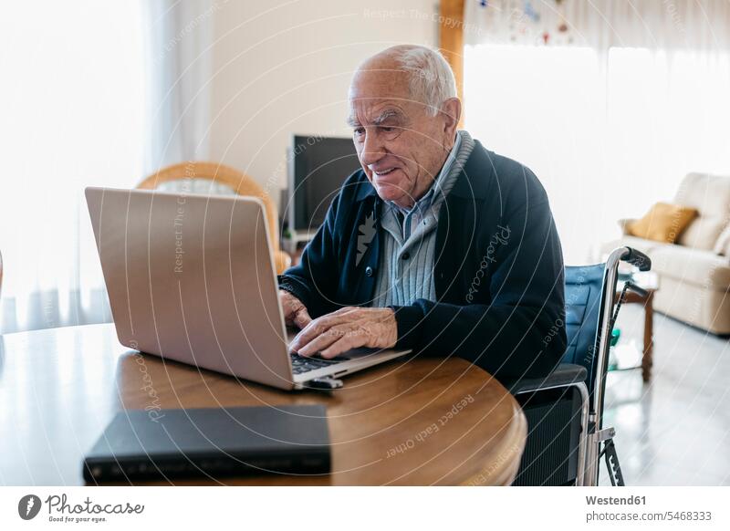 Portrait eines Seniormanns im Rollstuhl mit Laptop zu Hause Leute Menschen People Person Personen Europäisch Kaukasier kaukasisch 1 Ein ein Mensch