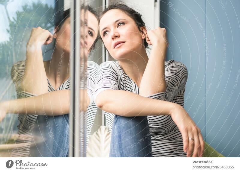 Ernste Frau schaut aus dem Fenster zu Hause schauen sehend sitzen sitzend sitzt ernst Ernsthaftigkeit ernsthaft Zuhause daheim weiblich Frauen Erwachsener