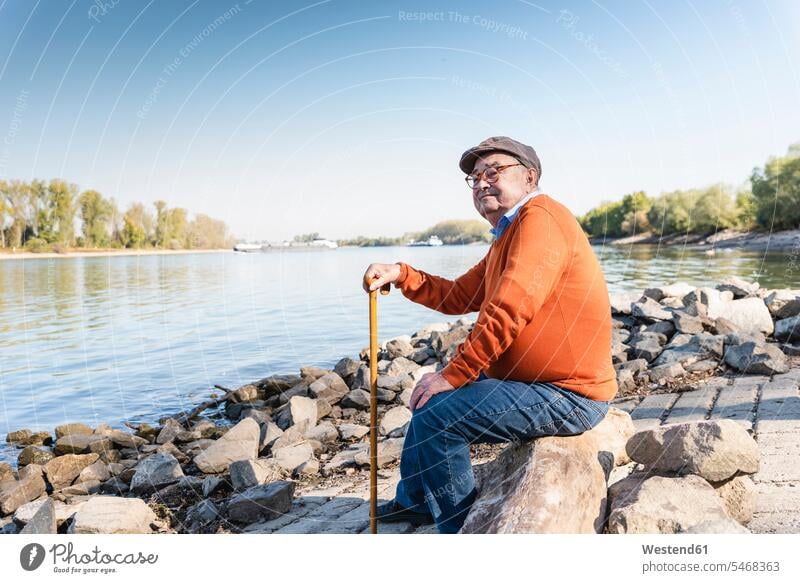 Alter Mann sitzt am Fluss Zuversicht Zuversichtlich Selbstvertrauen selbstbewusst Vertrauen Fluesse Fluß Flüsse sitzen sitzend Käppi Mütze Kappe Kaeppis Mützen