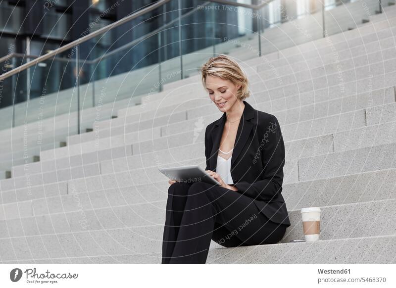 Blonde Geschäftsfrau mit Kaffee zu gehen sitzen auf der Treppe mit Tablette Geschäftsfrauen Businesswomen Businessfrauen Businesswoman Tablet Computer Tablet-PC