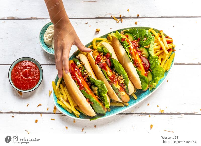 Hot Dogs mit Pommes frites, Ketchup und Mayonnaise, die Hand nimmt einen Hot Dog Ungesunde Ernährung ungesund essen essend Hände Mädchen weiblich nehmen