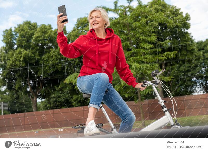 Ältere Frau mit Stadtrad mit Mobiltelefon weiblich Frauen Handy Handies Handys Mobiltelefone Zuversicht Zuversichtlich Selbstvertrauen selbstbewusst Vertrauen