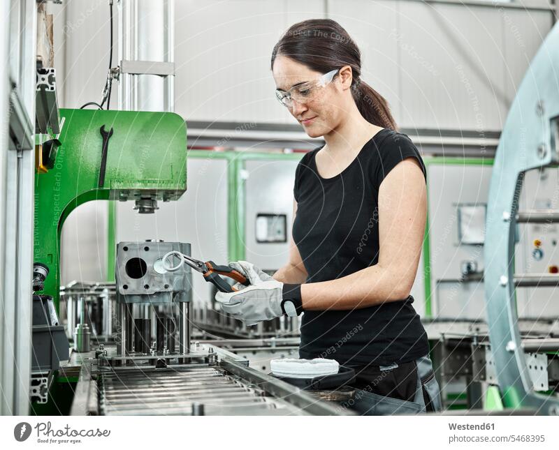 Junge Frau arbeitet an einer Maschine Österreich Arbeiterin Arbeiterinnen Metallverarbeitung Kompetenz Fähigkeit Können Metallbau Zange Zangen Sachverstand