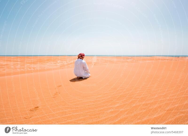 Beduine in Nationaltracht beim Beten in der Wüste, Rückansicht, Wahiba Sands, Oman Person aus dem Nahen Osten Personen aus dem Nahen Osten Dischdascha beten