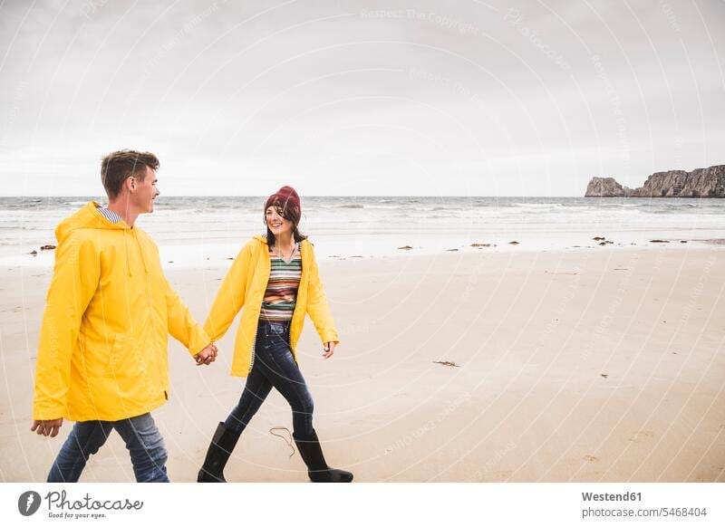 Junge Frau in gelben Regenjacken und Strandspaziergang, Bretagne, Frankreich Leute Menschen People Person Personen Europäisch Kaukasier kaukasisch 2 2 Menschen