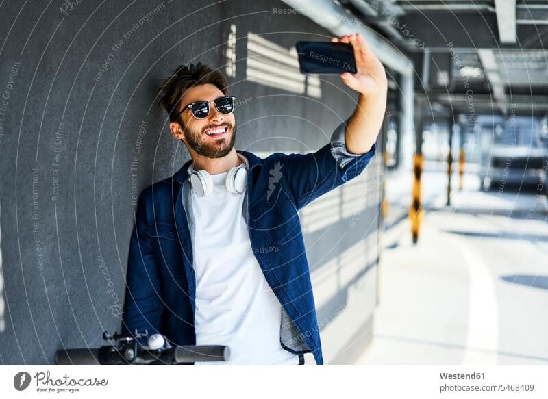 Porträt eines lächelnden Mannes, der mit seinem Smartphone ein Selfie macht iPhone Smartphones Selfies Portrait Porträts Portraits Männer männlich Handy