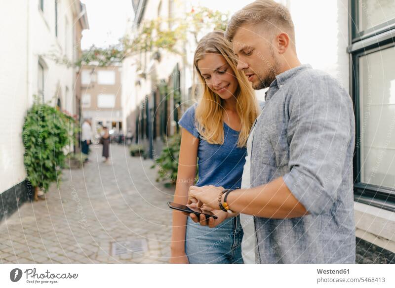 Niederlande, Maastricht, junges Paar schaut auf Handy die Stadt Mobiltelefon Handies Handys Mobiltelefone Pärchen Paare Partnerschaft staedtisch städtisch