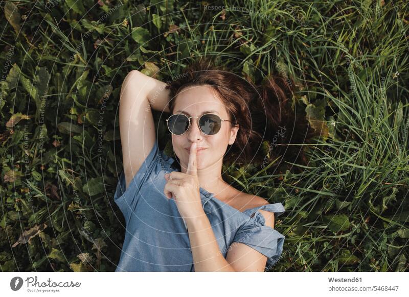 Porträt einer lächelnden Frau mit Sonnenbrille im Gras liegend liegt Sonnenbrillen Brille weiblich Frauen Portrait Porträts Portraits Erwachsener erwachsen