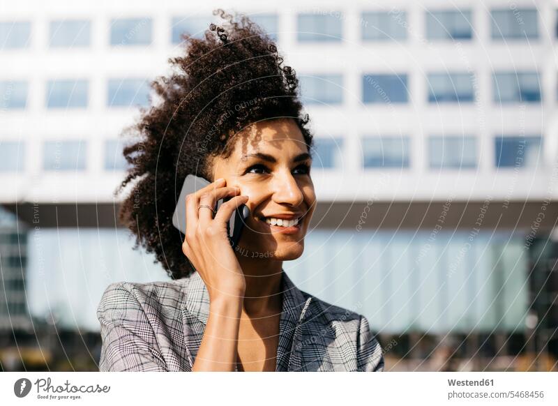 Porträt einer lächelnden Geschäftsfrau am Handy vor einem Bürogebäude telefonieren anrufen Anruf telephonieren Geschäftsfrauen Businesswomen Businessfrauen