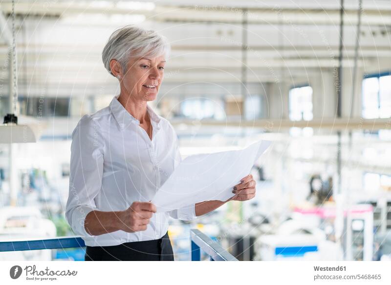 Ältere Frau schaut auf Plan in einer Fabrik ansehen weiblich Frauen Fabriken Pläne schauen sehend Erwachsener erwachsen Mensch Menschen Leute People Personen