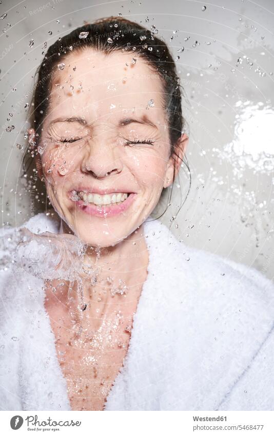Wasser spritzt einer glücklichen Frau im Bademantel ins Gesicht Bademäntel freuen Frohsinn Fröhlichkeit Heiterkeit Glück glücklich sein glücklichsein gefühlvoll