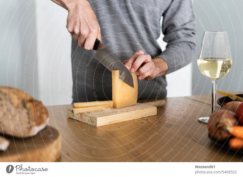 Nahaufnahme eines Mannes, der Käse auf der Küchentheke schneidet Farben Farbtoene Farbton Farbtöne graue grauer graues daheim zu Hause Lifestyles Essen