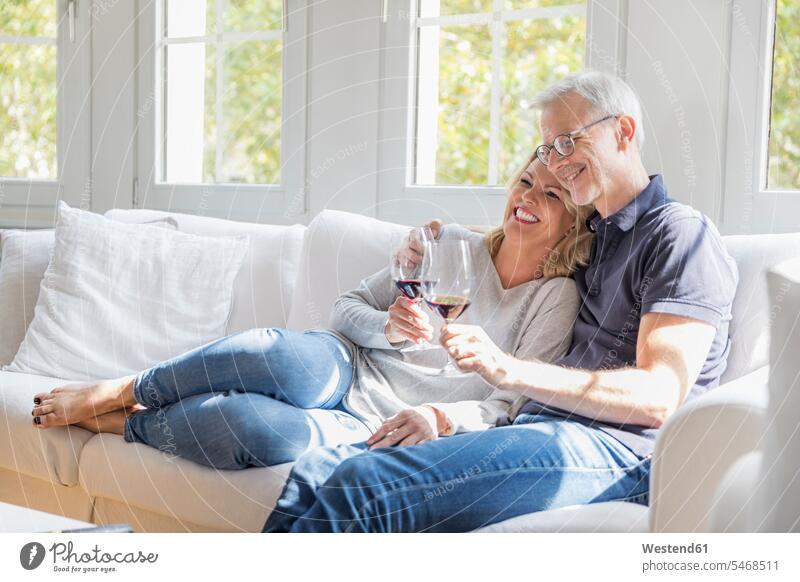 Reifes Paar entspannt sich auf der Couch bei Rotwein und hat Spaß Sofa Couches Liege Sofas Spass Späße spassig Spässe spaßig Pärchen Paare Partnerschaft