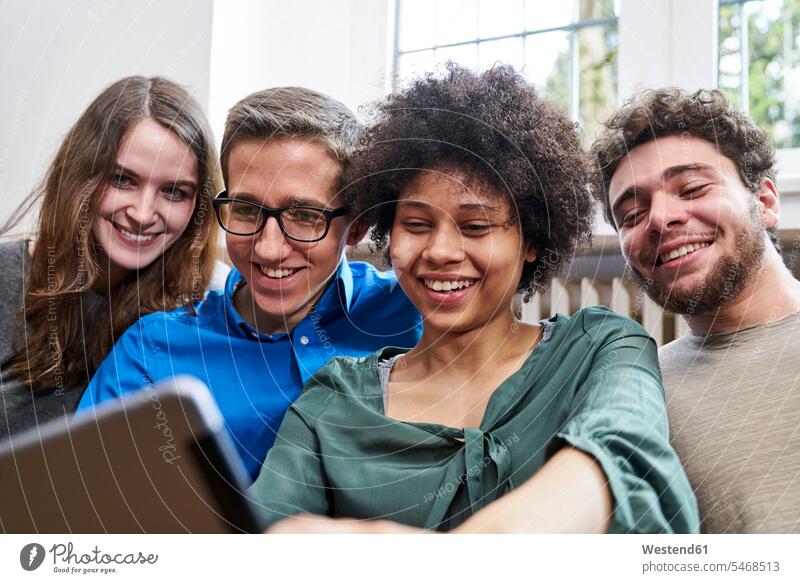 Lächelnde junge Leute schauen auf die Tablette lächeln ansehen Tablet Computer Tablet-PC Tablet PC iPad Tablet-Computer sehend Rechner Teamwork Teamarbeit