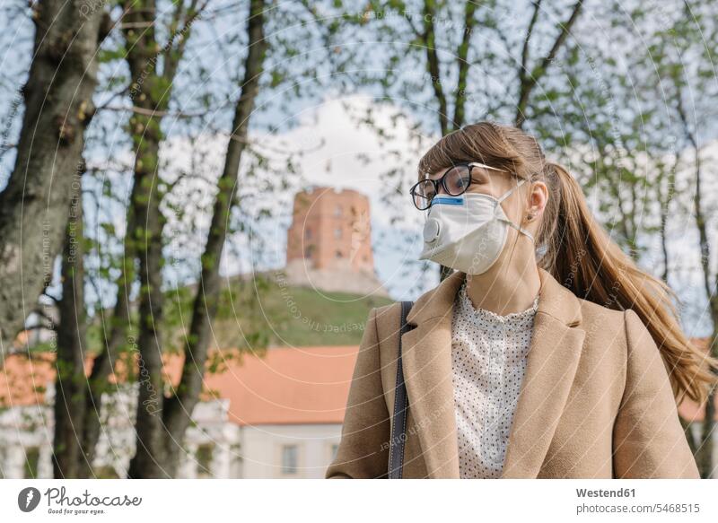 Frau mit FFP2-Maske, die in der Stadt seitwärts blickt Brillen stehend steht Muße geschützt schützen Absicherung außen draußen im Freien staedtisch städtisch
