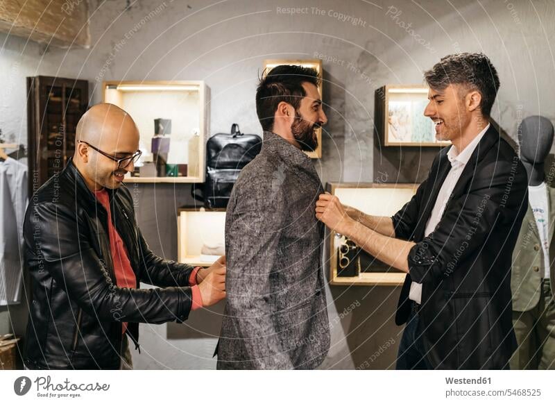 Zwei Männer arbeiten an neuem stilvollen Look für gut aussehenden Mann im Ausstellungsraum Kunde Kunden Kundschaft Herrenmode Geschäft Shop Laden Läden