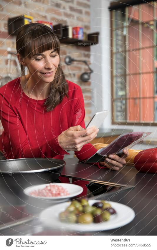 Frau in der Küche scannt Produkte mit ihrem Smartphone überprüfen testen checken iPhone Smartphones Küchen scannen Handy Mobiltelefon Handies Handys
