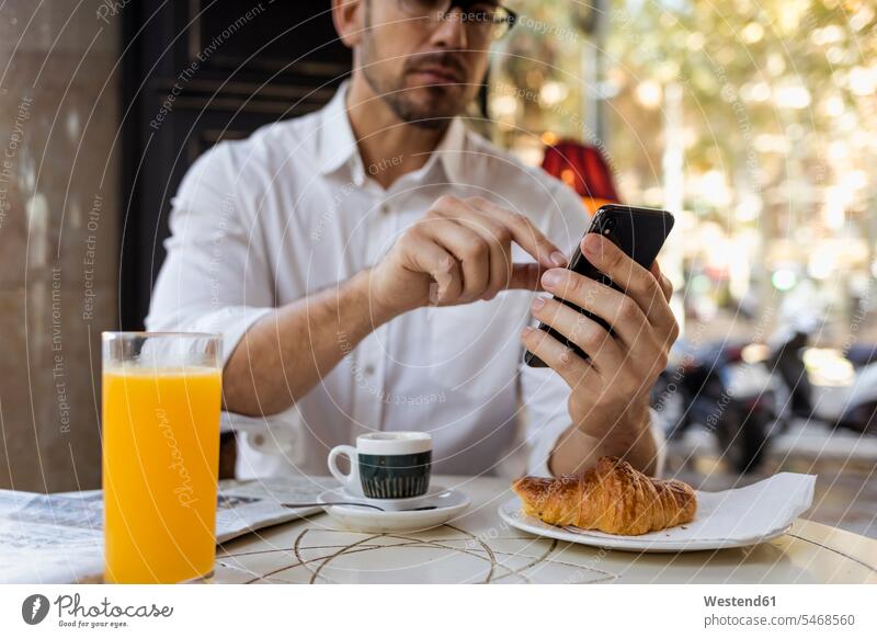 Geschäftsmann, der in einem Café frühstückt und ein Mobiltelefon benutzt Frühstück frühstücken Cafe Kaffeehaus Bistro Cafes Cafés Kaffeehäuser Businessmann