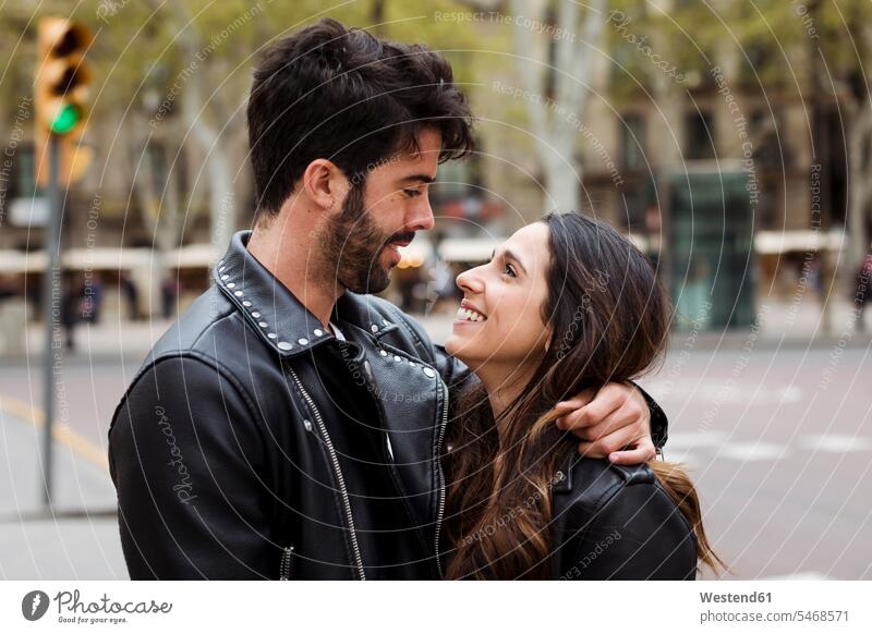 Spanien, Barcelona, glückliches junges Paar, das sich auf der Straße umarmt Glück glücklich sein glücklichsein umarmen Umarmung Umarmungen Arm umlegen Strassen